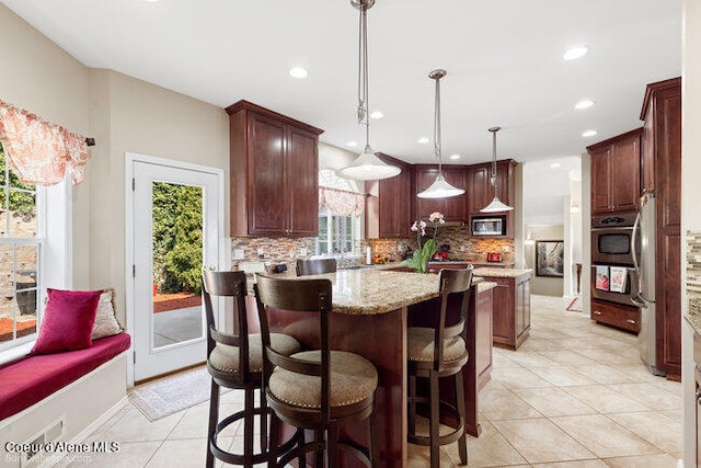 kitchen featuring decorative light fixtures, light tile patterned floors, a kitchen island, and decorative backsplash