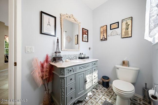 bathroom featuring toilet, vanity, and baseboards