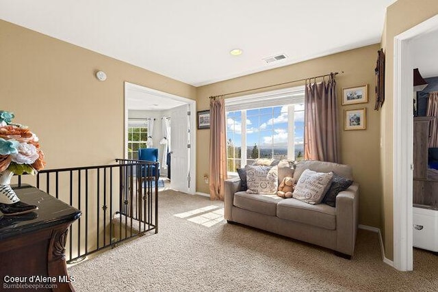 living area featuring baseboards, visible vents, an upstairs landing, and carpet flooring