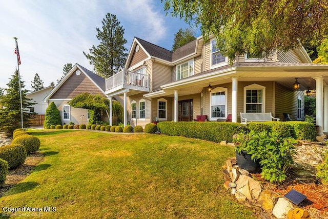 view of front of house featuring covered porch, a balcony, and a front yard