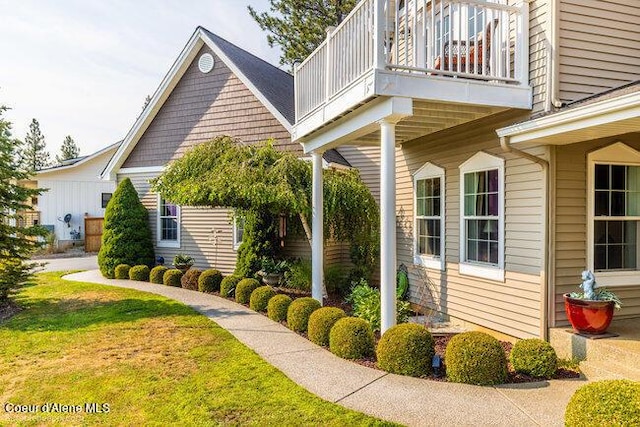 view of side of home with a yard and a balcony