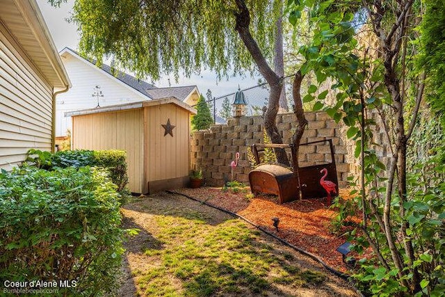 view of yard with fence, an outdoor structure, and a storage unit