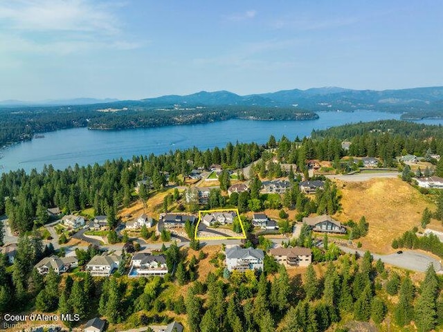 drone / aerial view featuring a residential view, a water and mountain view, and a view of trees