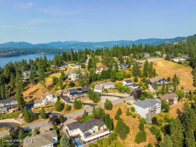aerial view featuring a water and mountain view, a wooded view, and a residential view