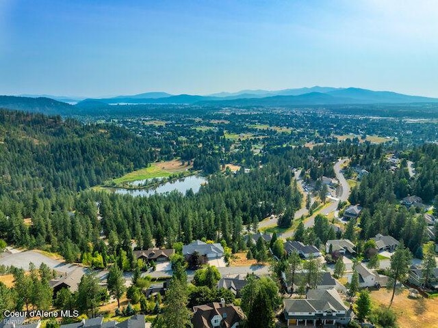 aerial view featuring a wooded view, a residential view, and a water and mountain view