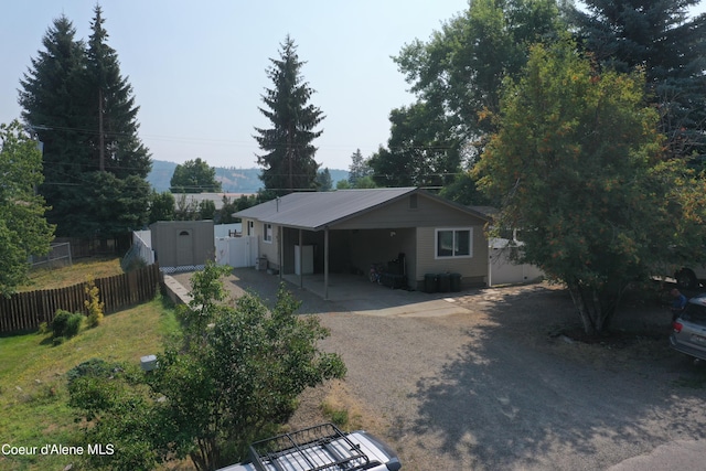 view of front of property with an outbuilding, dirt driveway, fence, cooling unit, and an attached carport