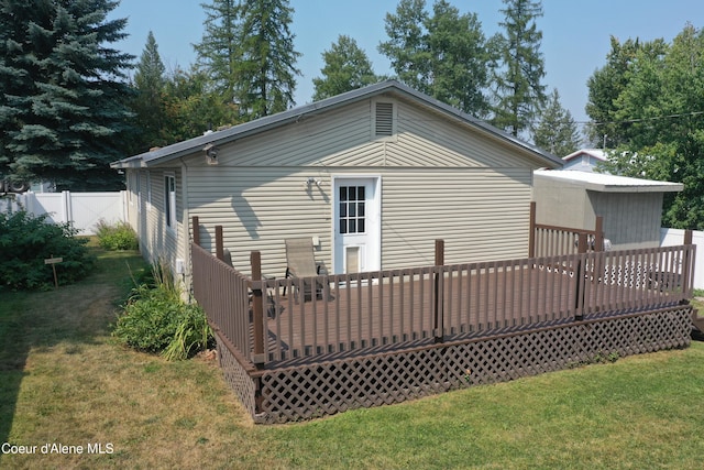 rear view of property with a lawn, a wooden deck, and fence