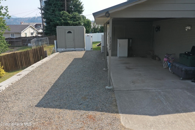 exterior space with fence, concrete driveway, and a shed