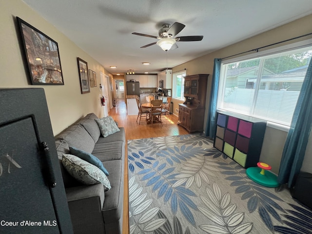 living area featuring light wood-type flooring and a ceiling fan