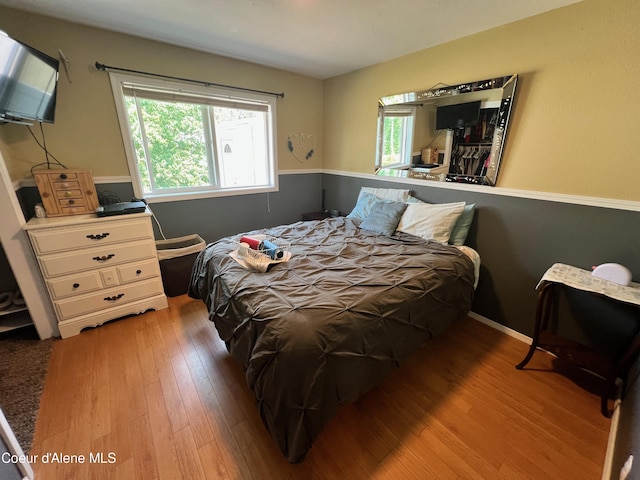 bedroom with multiple windows and hardwood / wood-style flooring