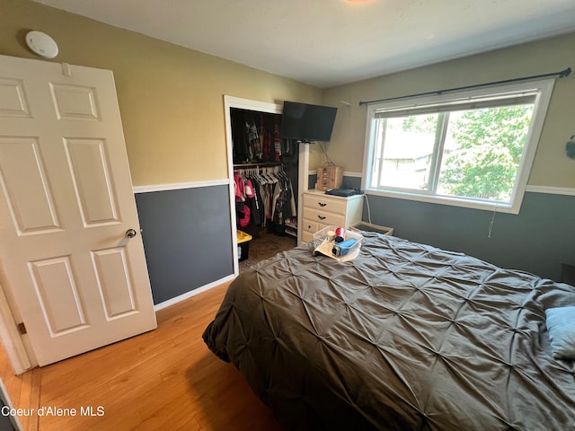 bedroom featuring light wood-style flooring, baseboards, and a closet