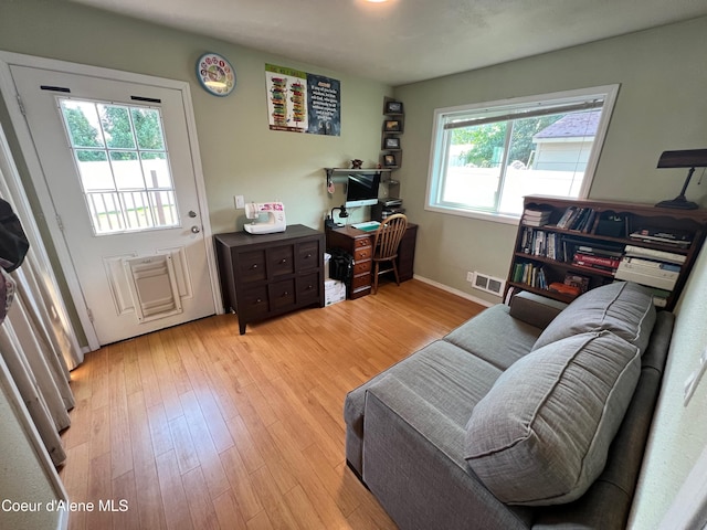 office space featuring light wood finished floors, visible vents, and baseboards