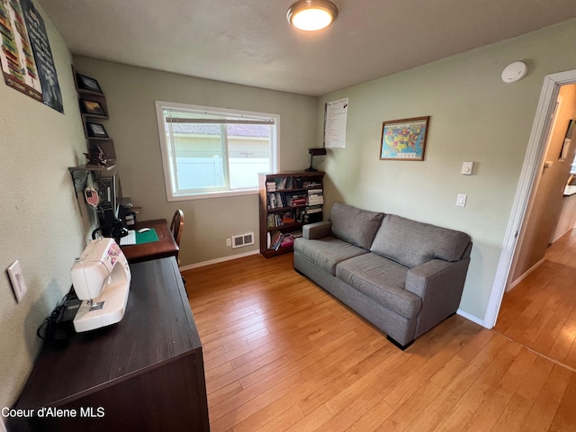 living area featuring light wood-style floors, visible vents, and baseboards