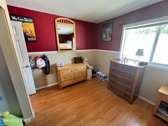 bedroom with baseboards, light wood-style floors, and a textured ceiling