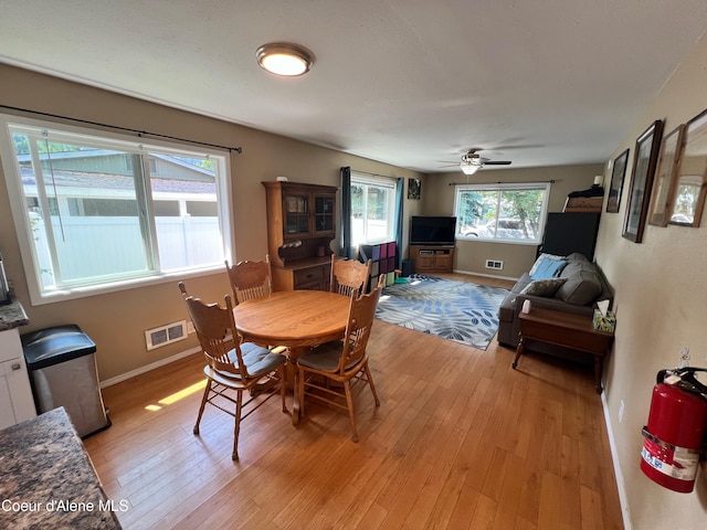 dining area with baseboards, visible vents, and light wood finished floors