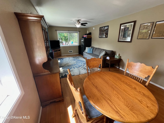 living area with visible vents, baseboards, a ceiling fan, and hardwood / wood-style flooring