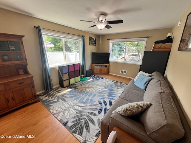 living room with a healthy amount of sunlight, baseboards, and light wood finished floors