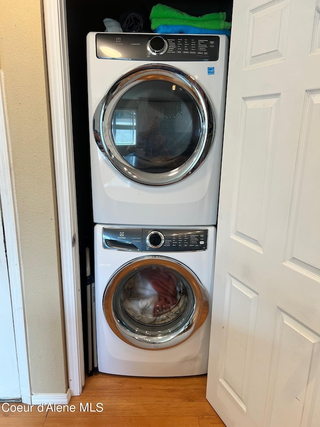 washroom with laundry area, light wood-style flooring, and stacked washer and dryer