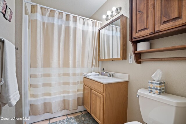 bathroom with tile patterned floors, curtained shower, vanity, and toilet