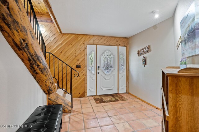 tiled foyer with wooden walls and a healthy amount of sunlight