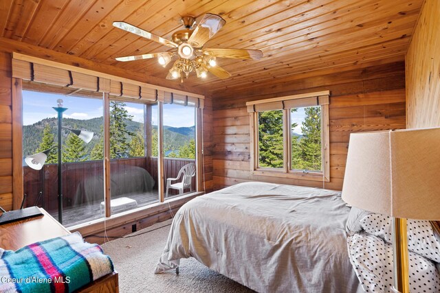 carpeted bedroom featuring ceiling fan, access to exterior, a mountain view, and multiple windows