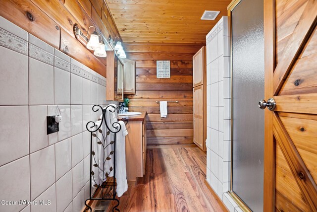 bathroom with vanity, wooden walls, hardwood / wood-style flooring, a shower with shower door, and wood ceiling