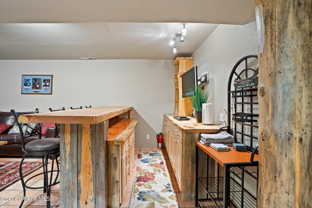 bar with butcher block counters and light tile patterned floors