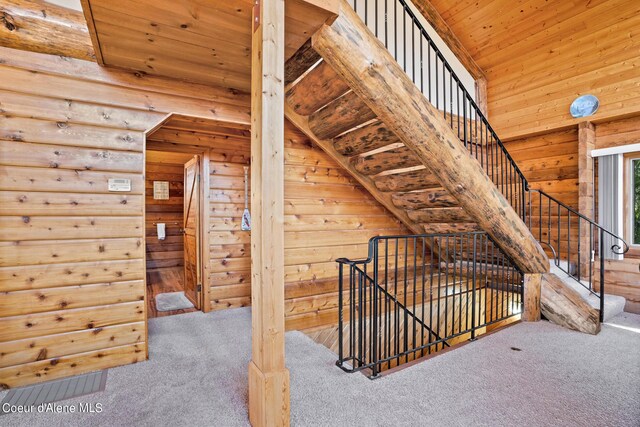 stairs featuring carpet flooring, wooden walls, and wood ceiling