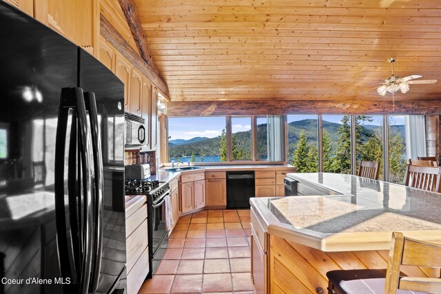 kitchen featuring a mountain view, light brown cabinets, wooden ceiling, black appliances, and light tile patterned floors