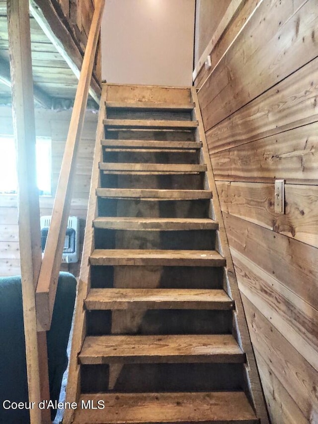 stairway featuring wooden walls