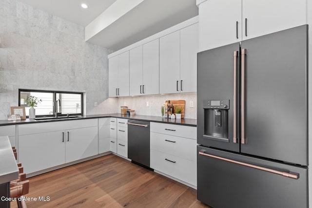 kitchen featuring white cabinets, dark countertops, dark wood-style flooring, stainless steel refrigerator with ice dispenser, and backsplash