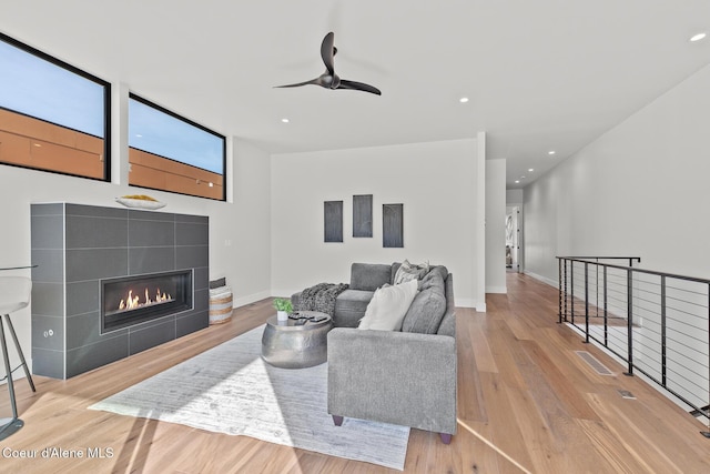 living area featuring baseboards, a fireplace, wood finished floors, and recessed lighting