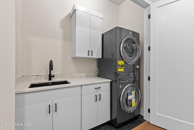 washroom featuring stacked washer / dryer, cabinet space, a sink, and tile patterned floors