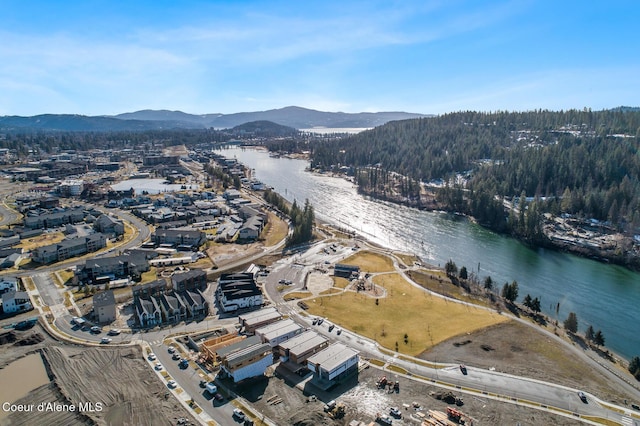 drone / aerial view featuring a wooded view and a water and mountain view