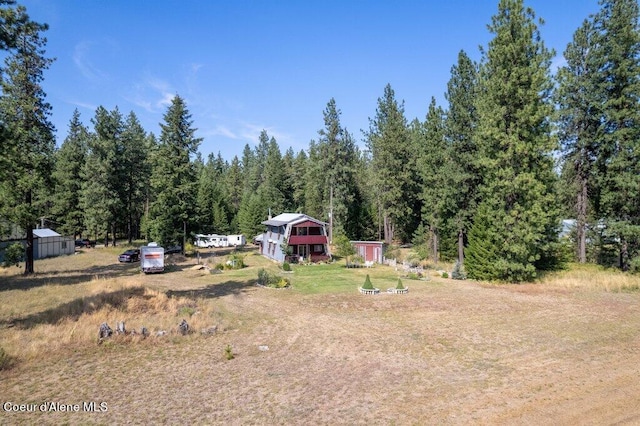view of yard featuring a forest view and an outbuilding