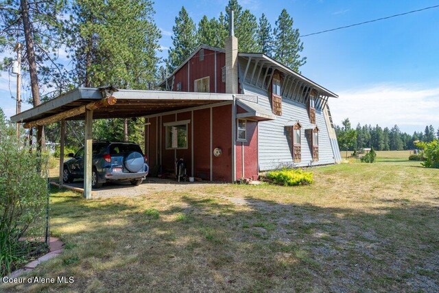exterior space with a chimney, a carport, driveway, and a yard
