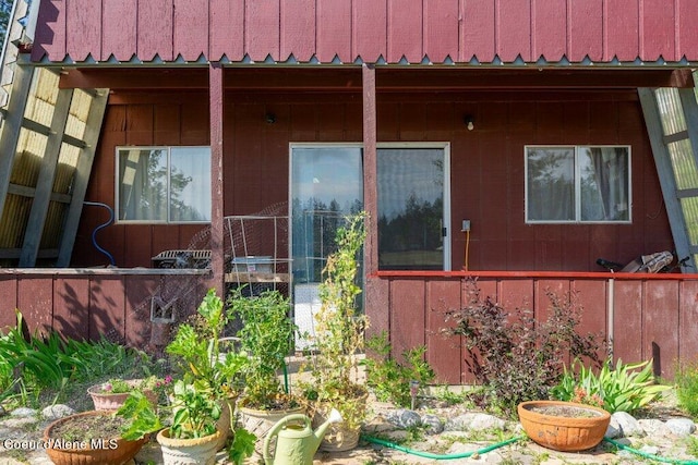 view of exterior entry featuring fence and board and batten siding