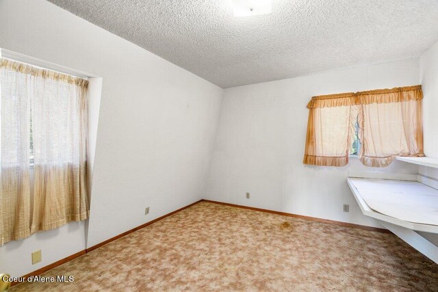 carpeted spare room with baseboards and a textured ceiling