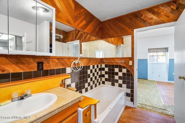 bathroom featuring wood finished floors, walk in shower, wooden walls, and a washtub
