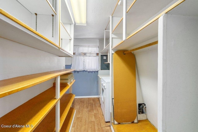 spacious closet with light hardwood / wood-style floors and washing machine and dryer