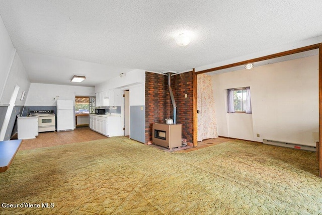 unfurnished living room featuring light hardwood / wood-style flooring, a wood stove, a baseboard radiator, and a textured ceiling