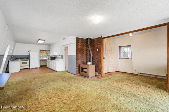 unfurnished living room with a textured ceiling, a baseboard heating unit, a wood stove, and light carpet