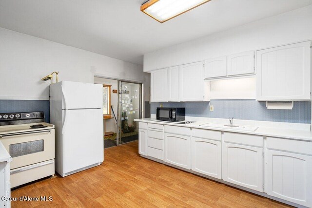 kitchen with light wood finished floors, a sink, white appliances, white cabinetry, and light countertops