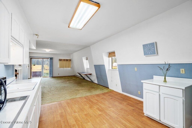 kitchen featuring light wood-type flooring, white cabinets, sink, and a wealth of natural light