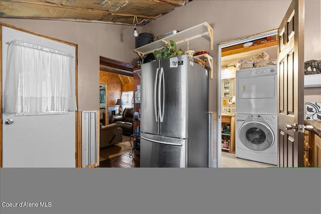 kitchen with stacked washing maching and dryer, light hardwood / wood-style flooring, and stainless steel refrigerator