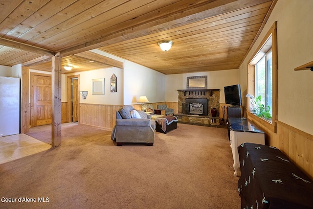 living room featuring beamed ceiling, carpet floors, wooden ceiling, and a stone fireplace