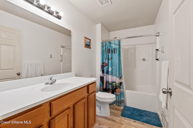 full bathroom with wood-type flooring, a textured ceiling, vanity, shower / bath combo, and toilet