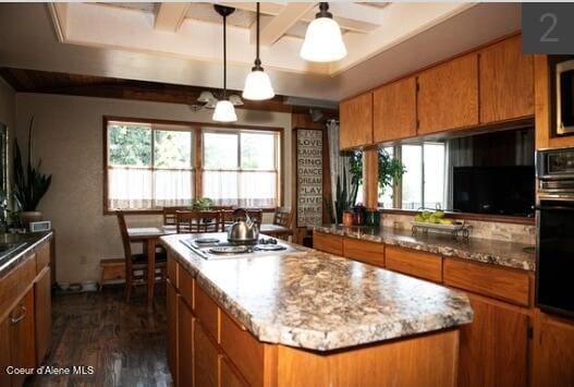 kitchen with a center island, dark wood-type flooring, beam ceiling, hanging light fixtures, and oven