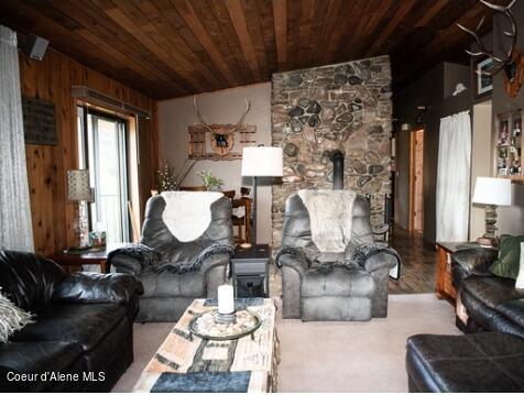 living room with wood ceiling, a wood stove, lofted ceiling, and wooden walls