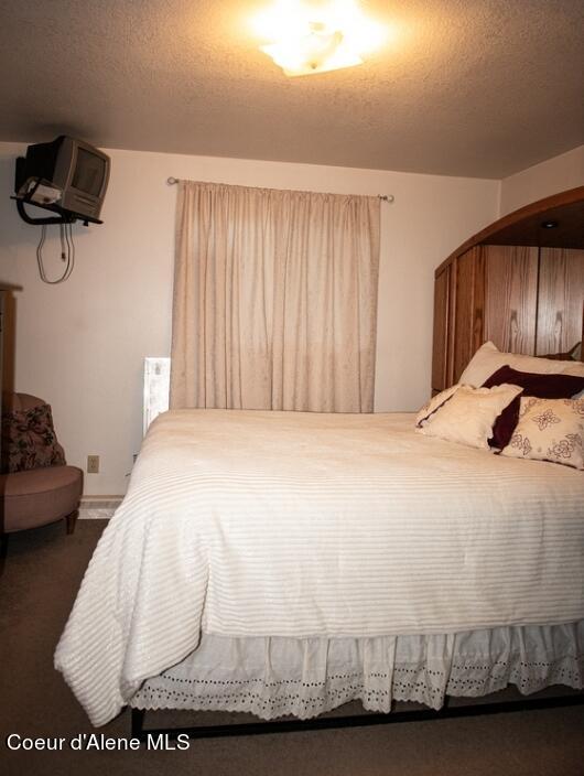 bedroom featuring a textured ceiling and dark colored carpet